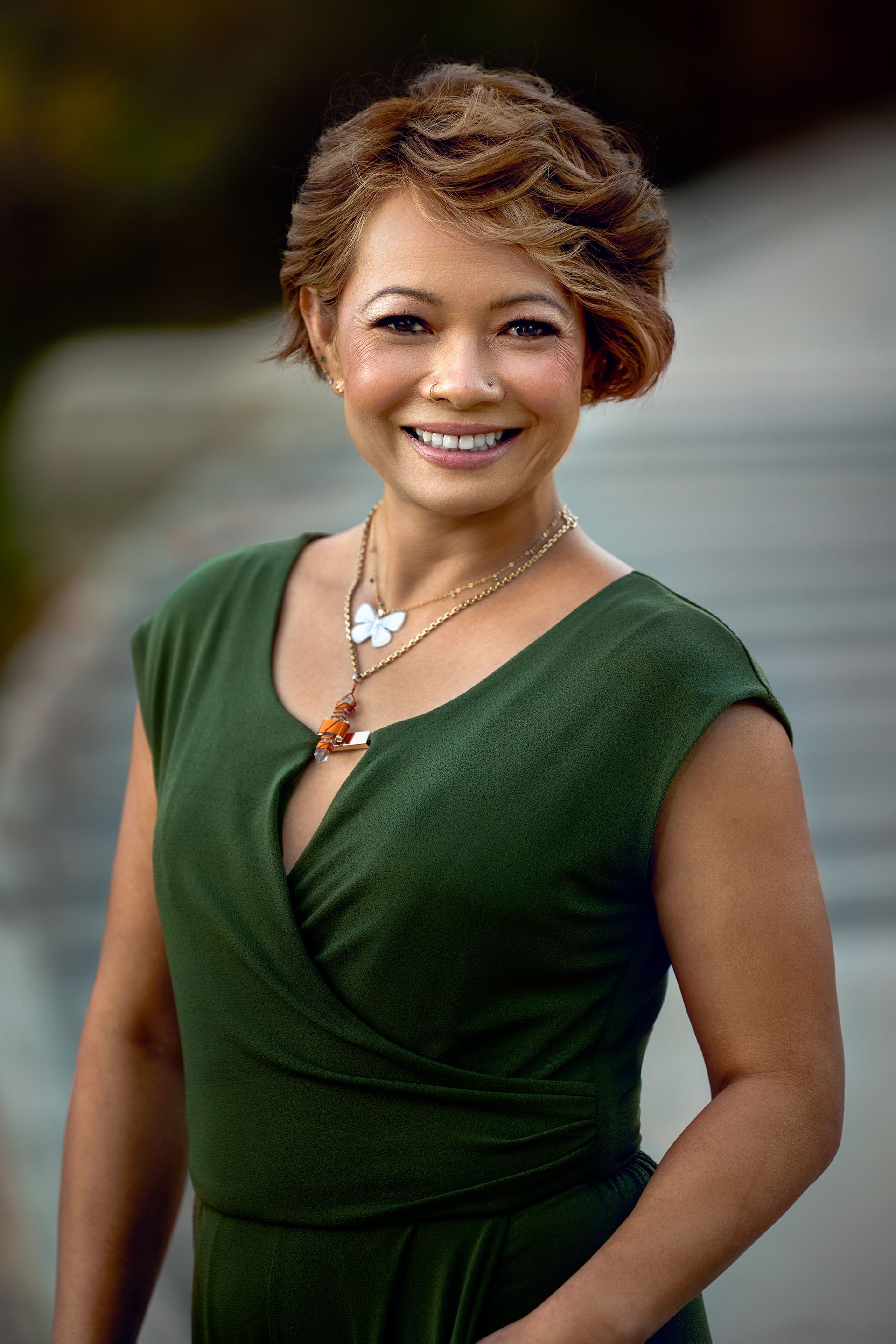 A woman is smiling on the beach and looking at the camera.
