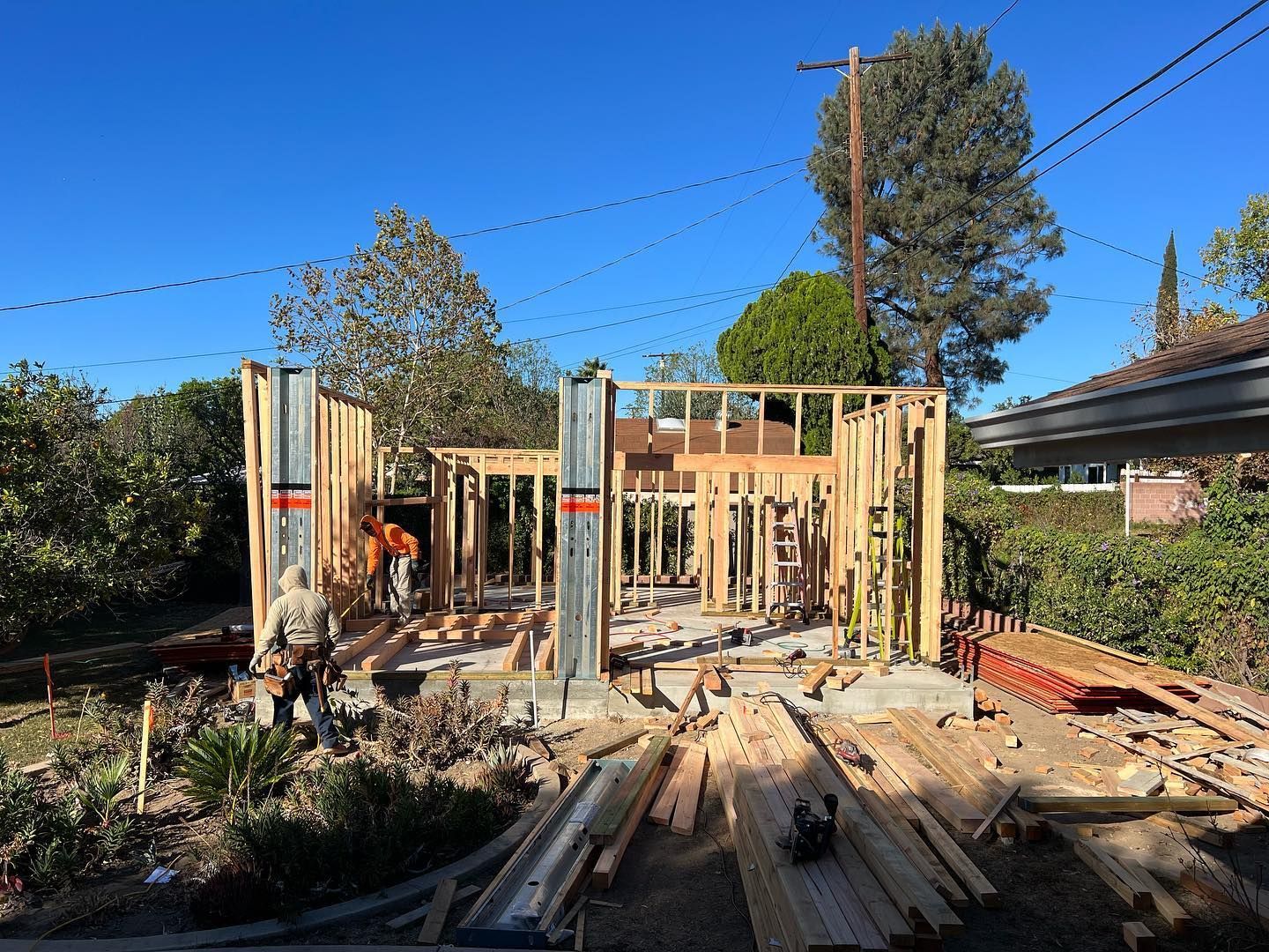 Back of a brown stucco house with a new concrete patio and windows on a sunny day.