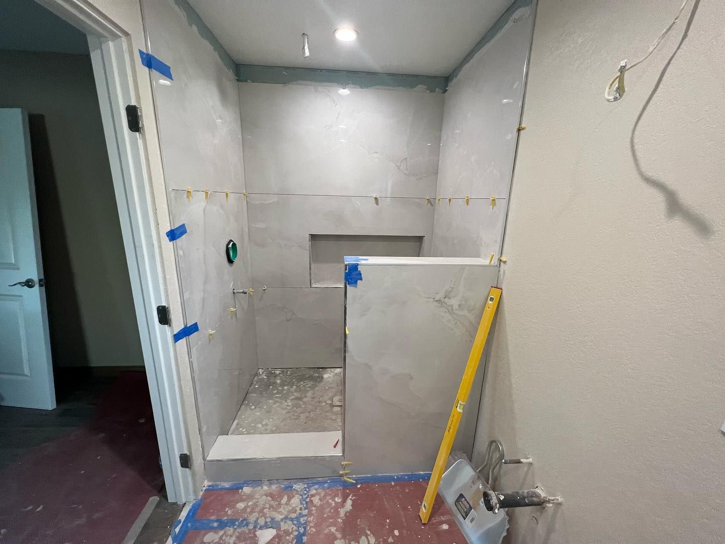 Bathroom with beige tile, brown vanity, white tub, and toilet. A mosaic tile strip accents the shower.