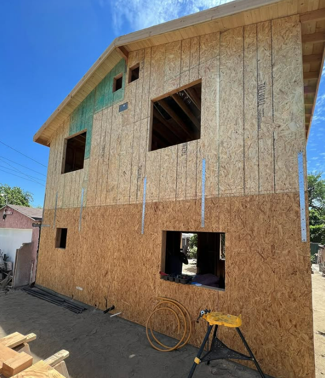 Tan ranch house with a garage and a small lawn; street and power pole in the foreground.