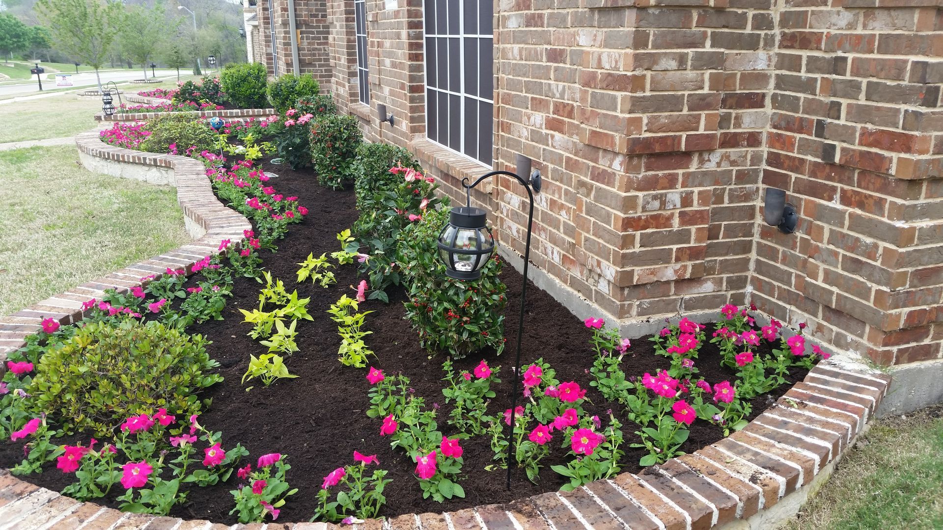 A brick house with a flower bed in front of it.
