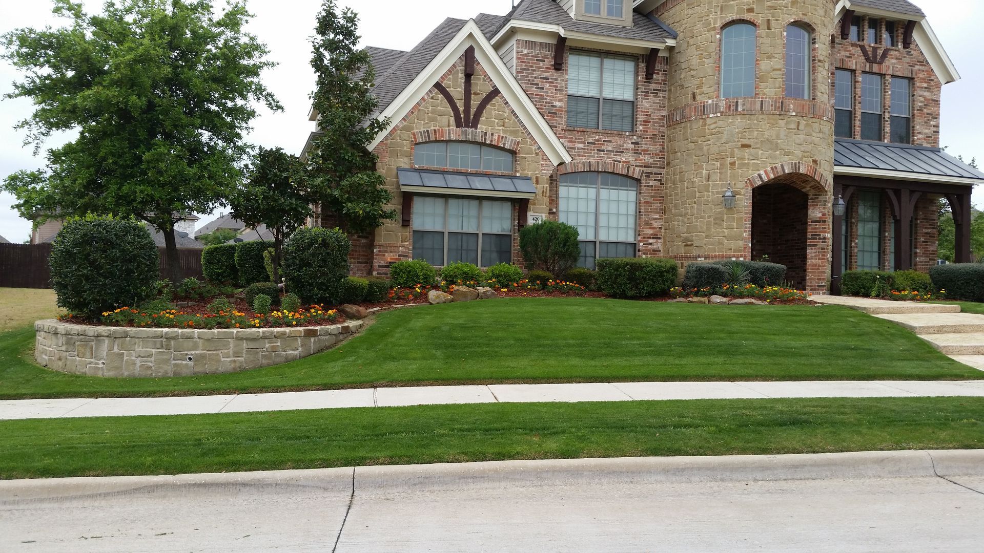 A large brick house with a lush green lawn in front of it