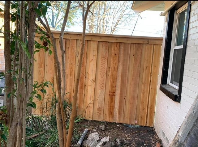 A wooden fence is in the backyard of a house.