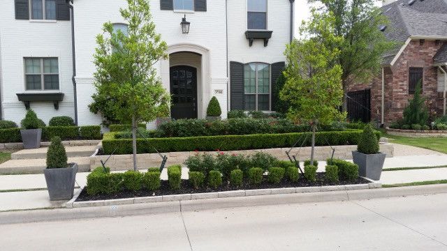 A white house with a lush green garden in front of it