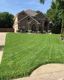 A large brick house with a lush green lawn in front of it.