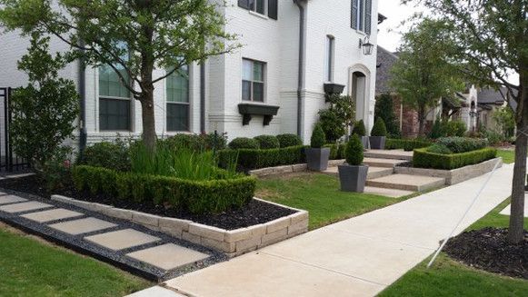 A white house with a lush green lawn and a sidewalk in front of it.