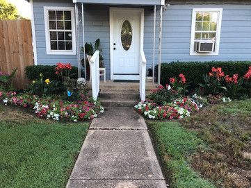 A blue house with a white door and a concrete walkway leading to it.