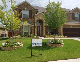 A large brick house with a yard meeting sign in front of it