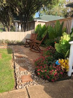 There are two rocking chairs in the backyard of a house.