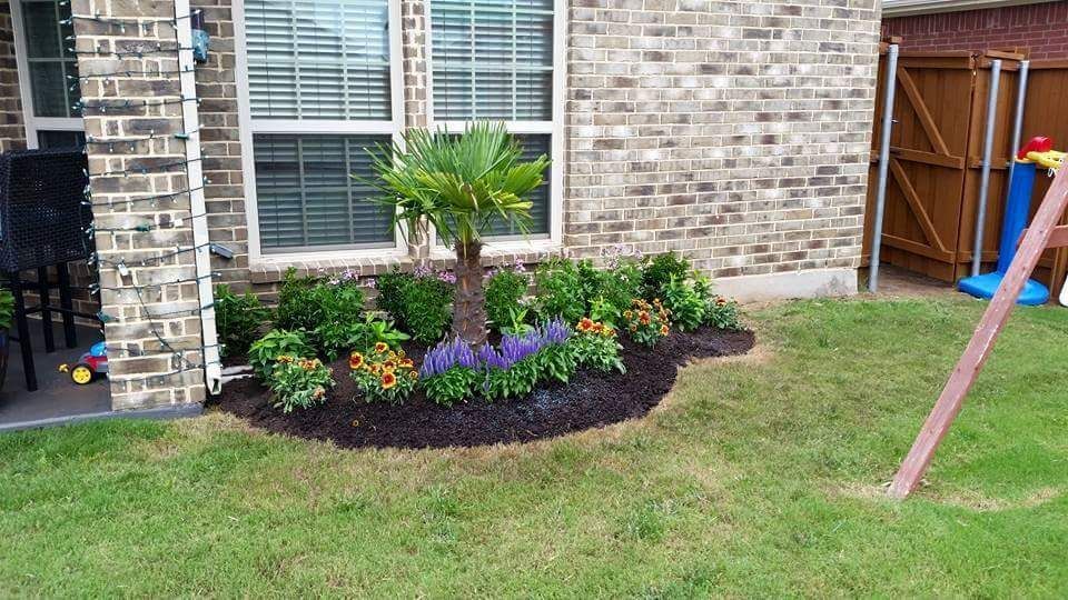 A sidewalk with a bed of flowers in front of a house.
