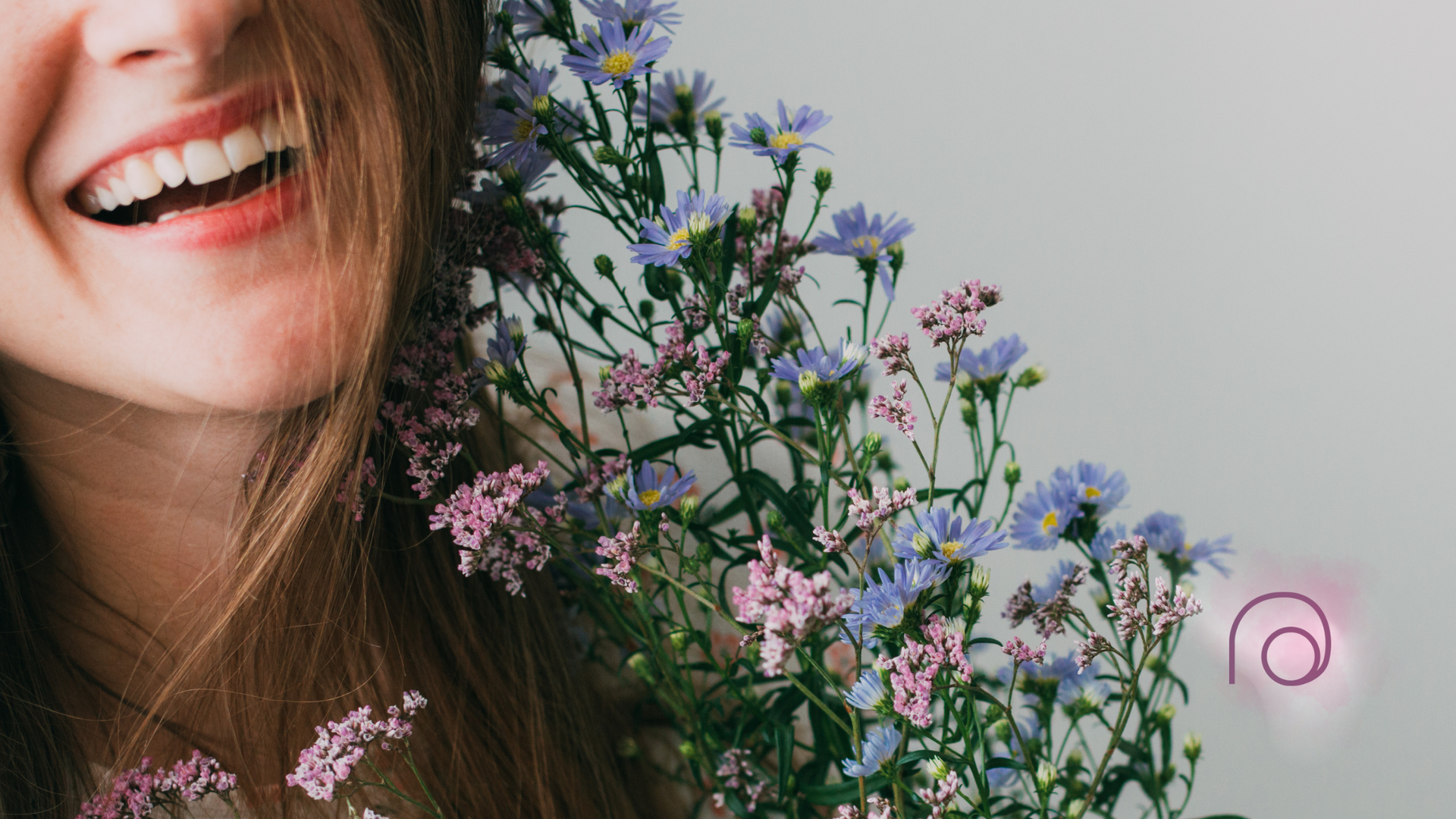 Smiling person with bouquet of purple and pink flowers.