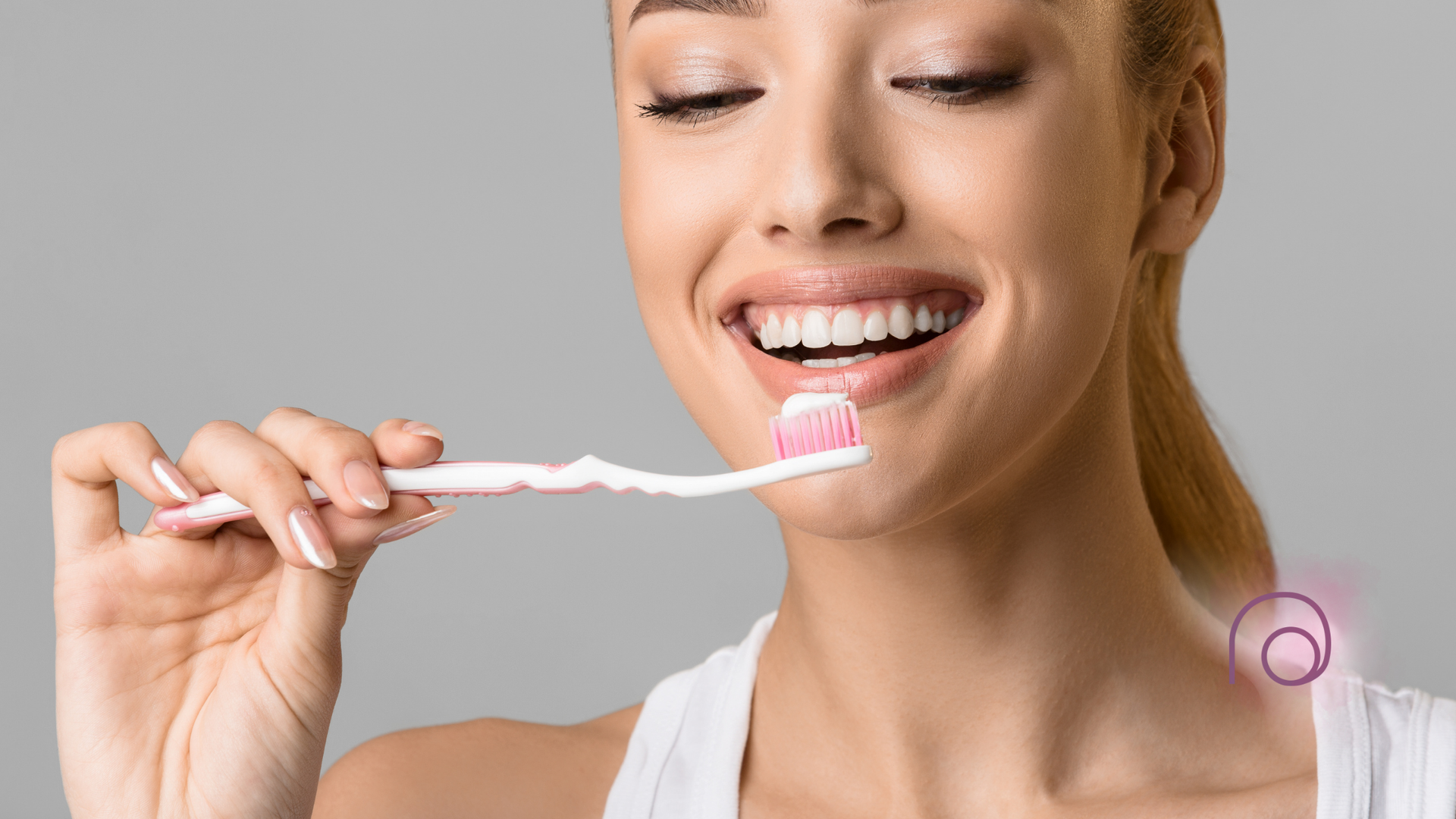 A woman is brushing her teeth with a pink toothbrush.