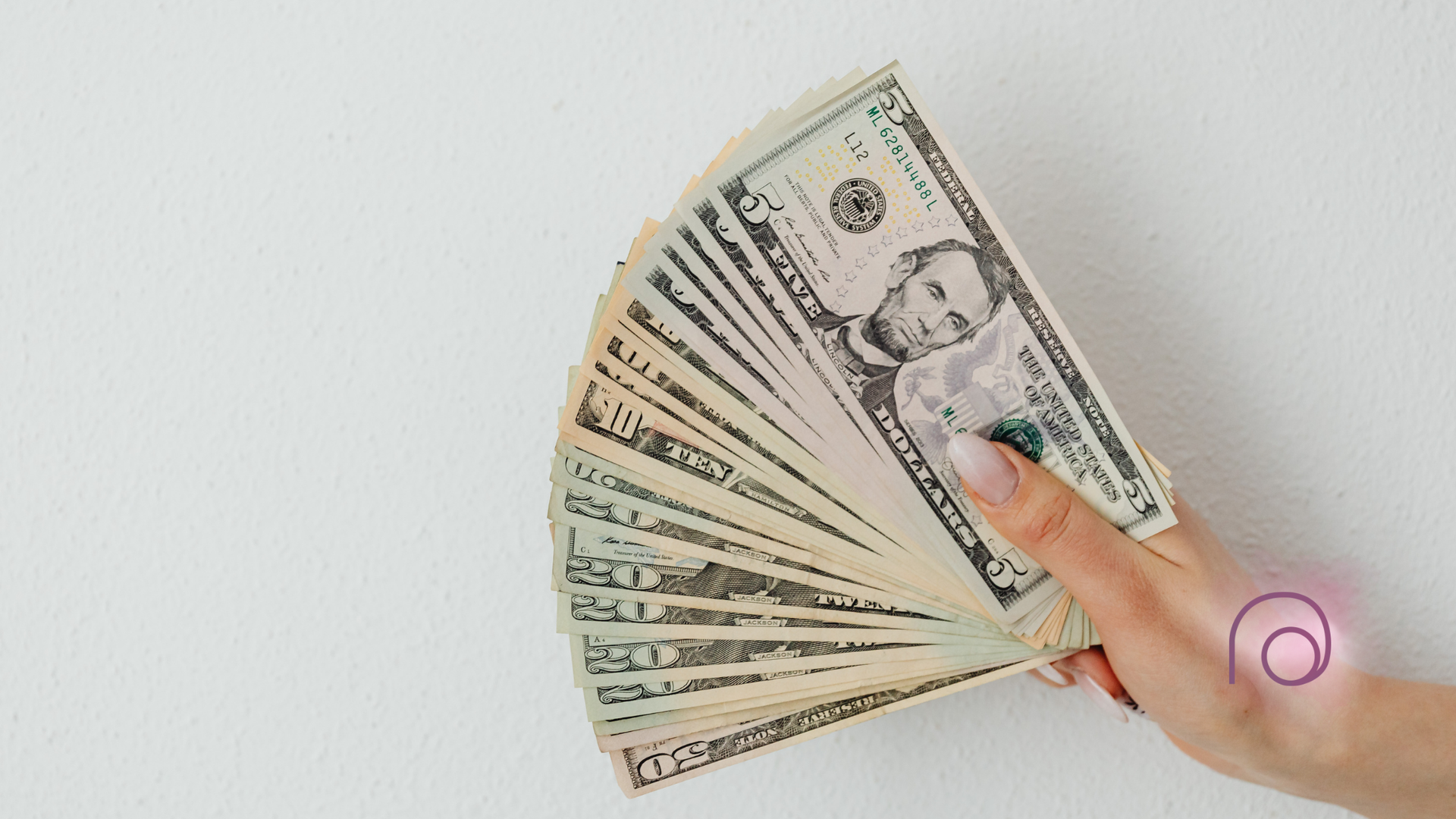 Hand holding fanned out US dollar bills against a white background.