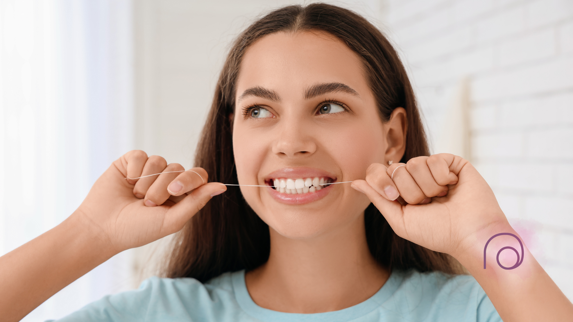 Smiling woman flossing her teeth with both hands in a bright bathroom