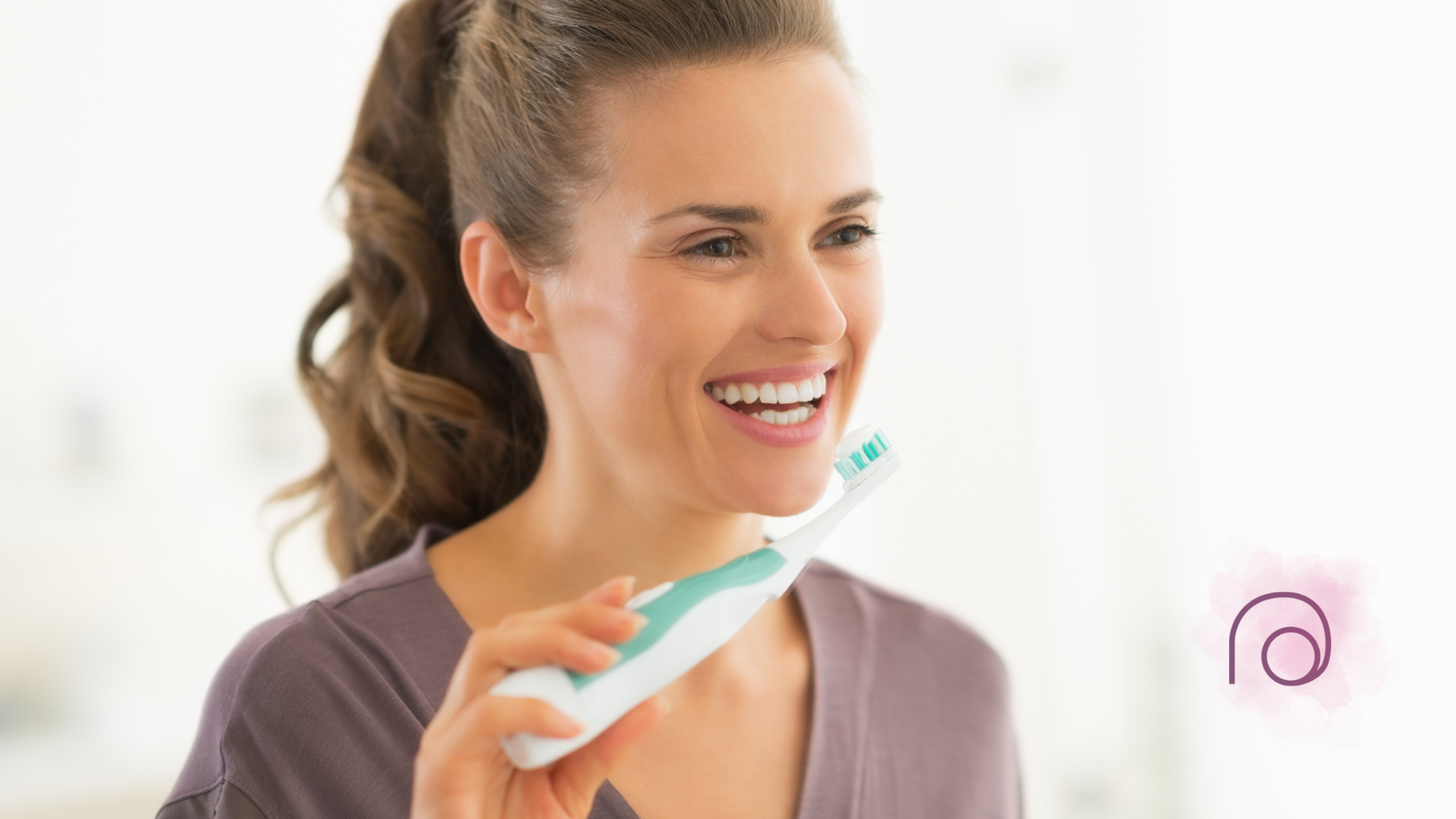 A woman is brushing her teeth with an electric toothbrush.