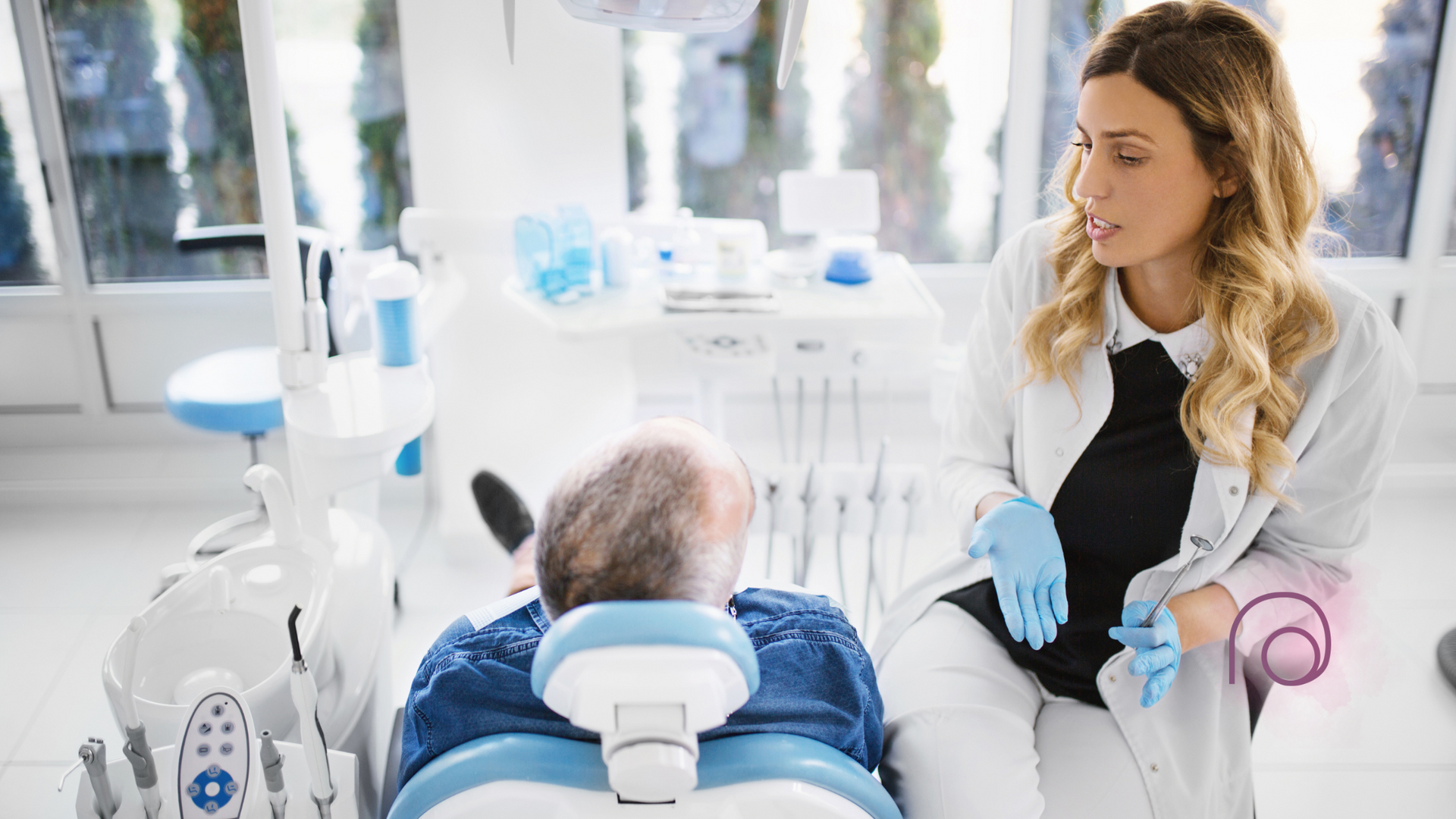 A dentist is talking to a patient in a dental chair.
