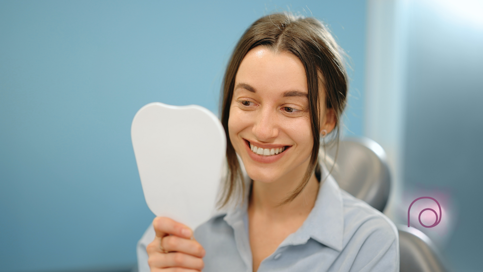 A woman is smiling while looking at her teeth in a mirror.