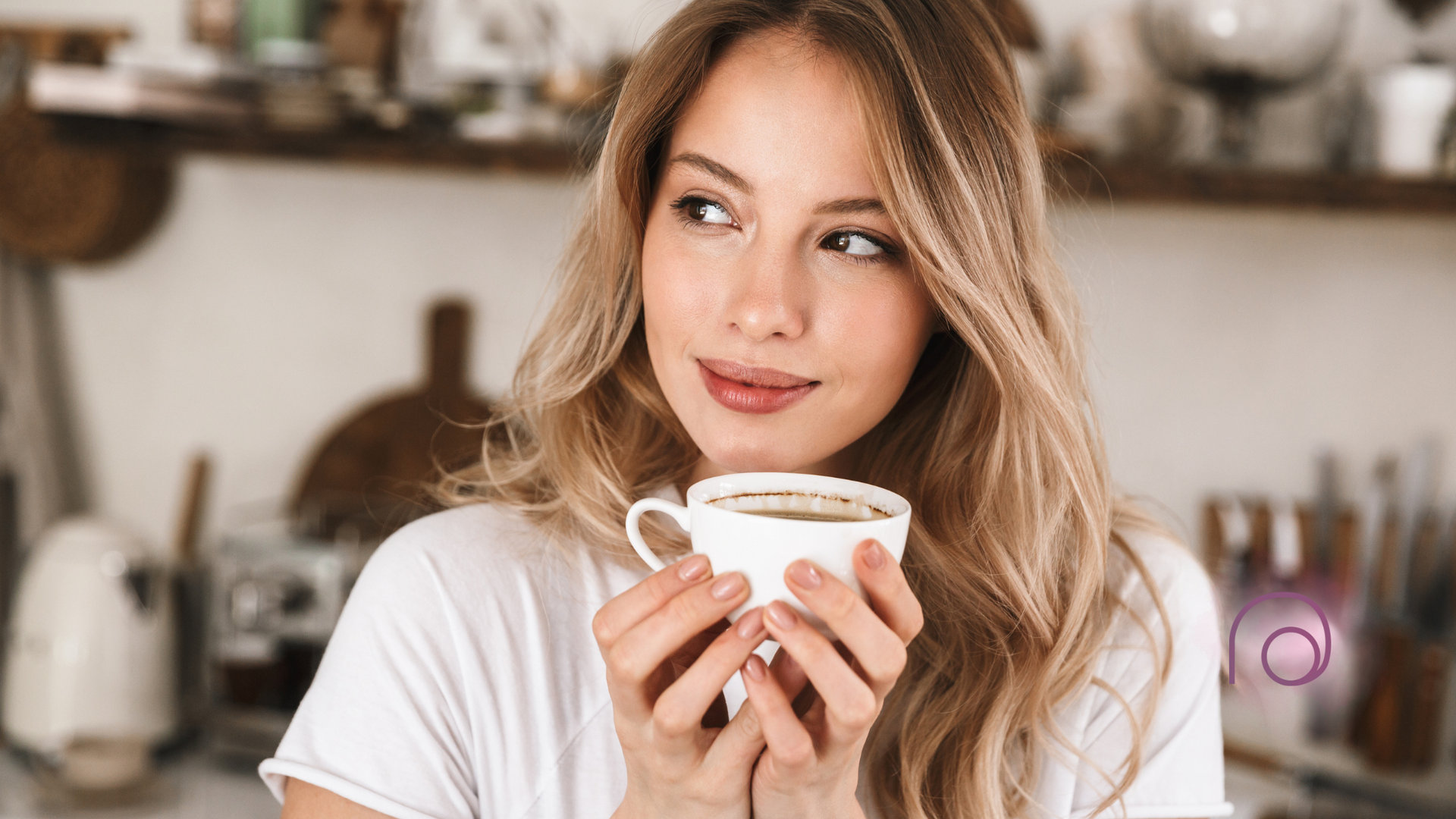 A woman is holding a cup of coffee in her hands in a kitchen.