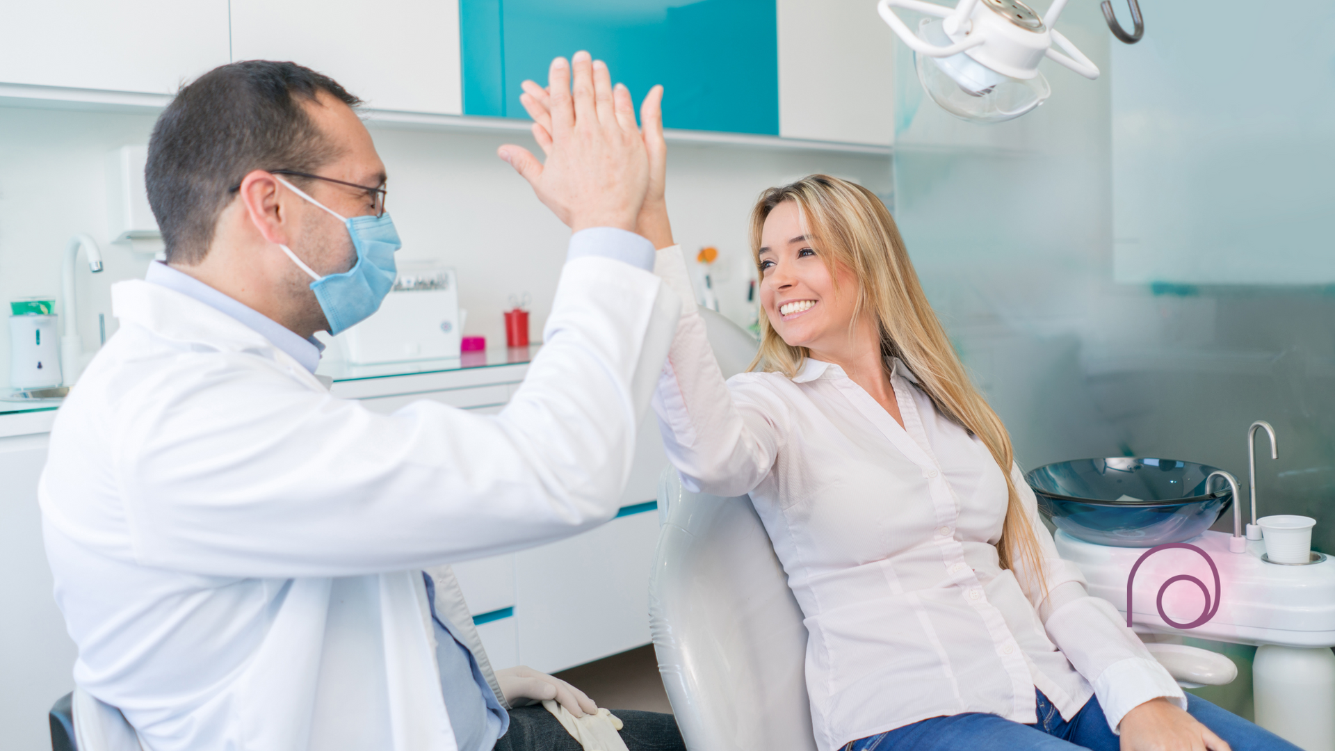 A dentist and a patient are giving each other a high five in a dental office.