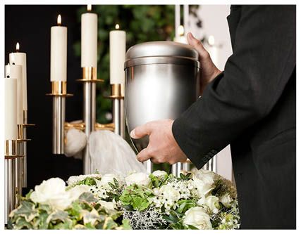 A black urn is surrounded by flowers and leaves