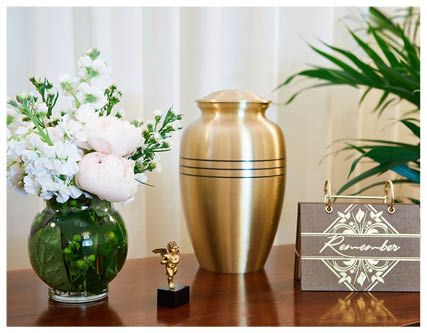 A black urn is surrounded by flowers and leaves