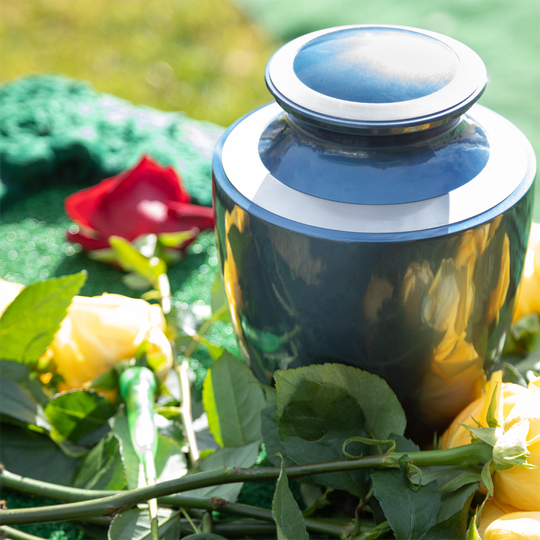 A black urn is surrounded by flowers and leaves