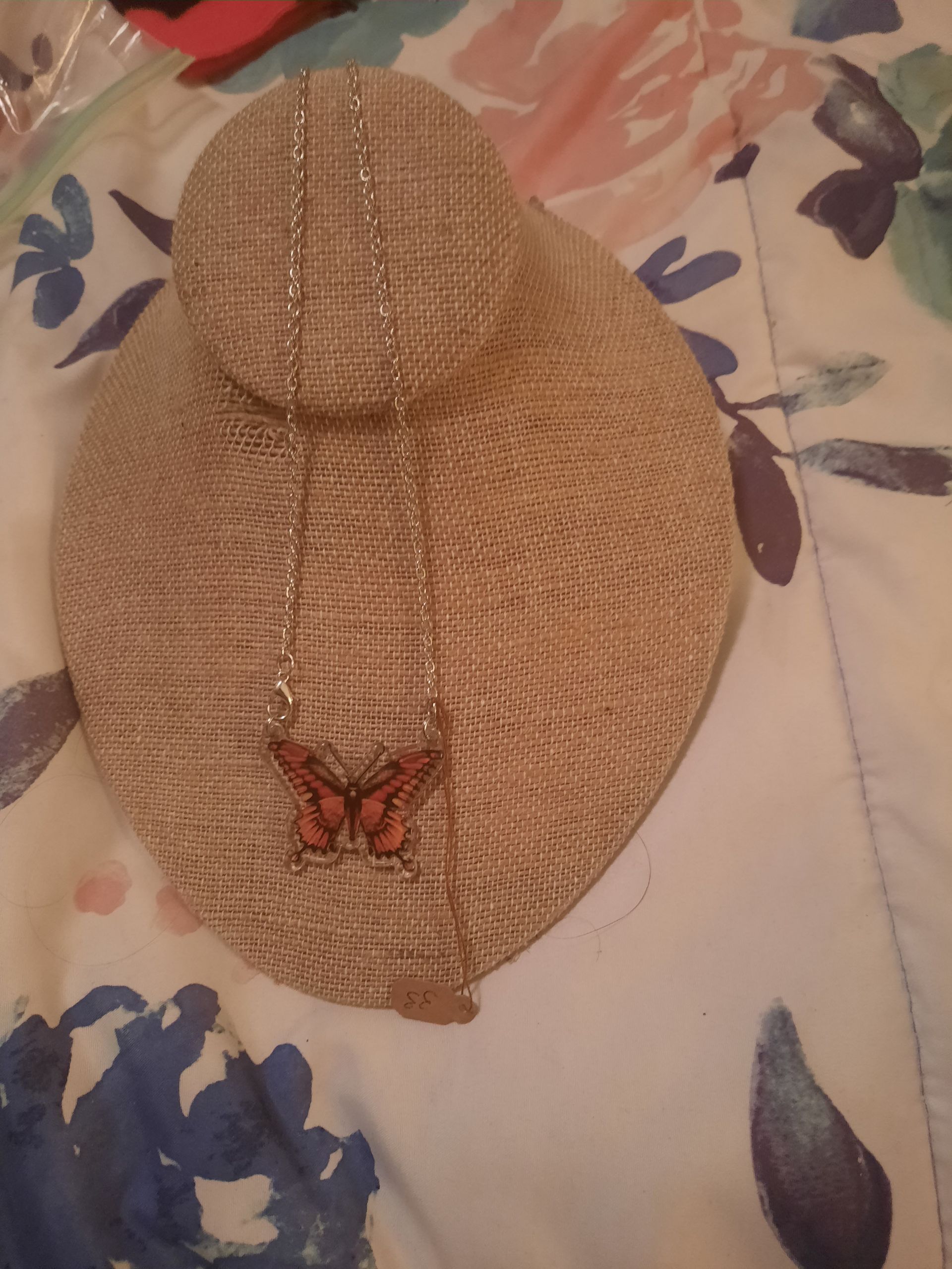 A necklace with a butterfly pendant is on a mannequin.