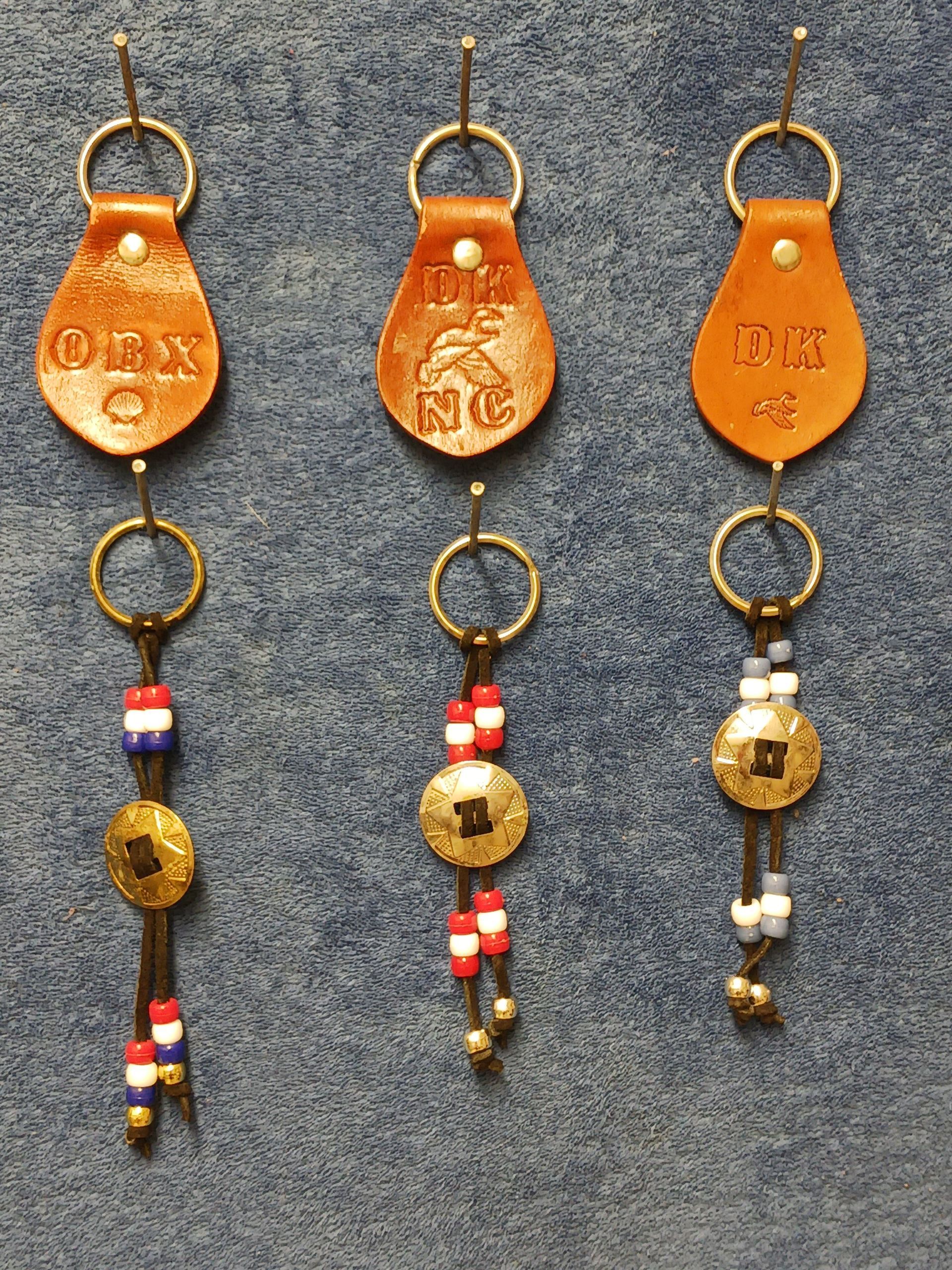 Three brown leather keychains with beads and coins on a blue surface