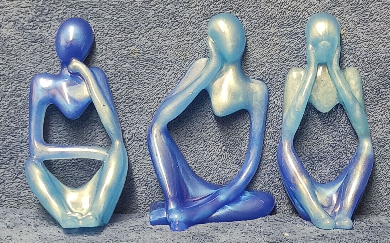Three resin blue figurines are sitting next to each other on a table