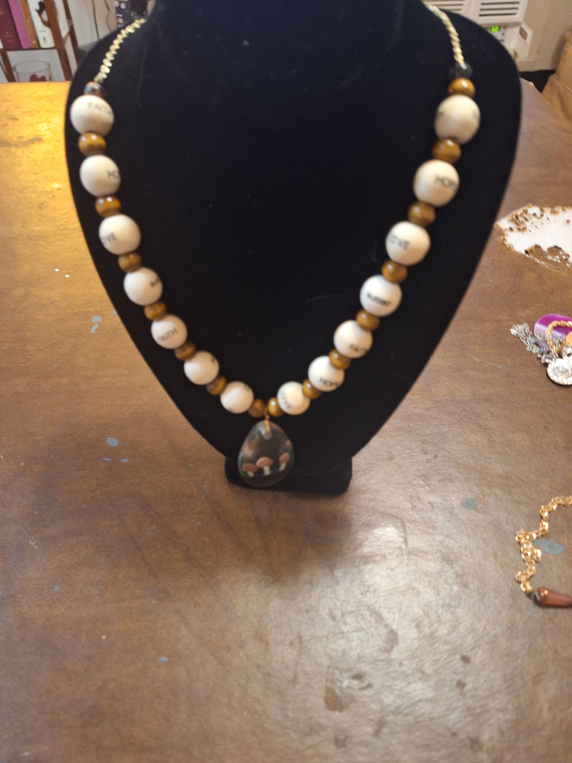 A necklace with white and gold beads is on a mannequin