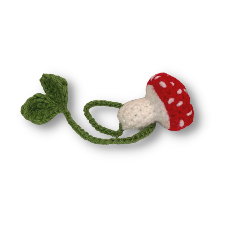 A red and white crocheted mushroom with a green stem