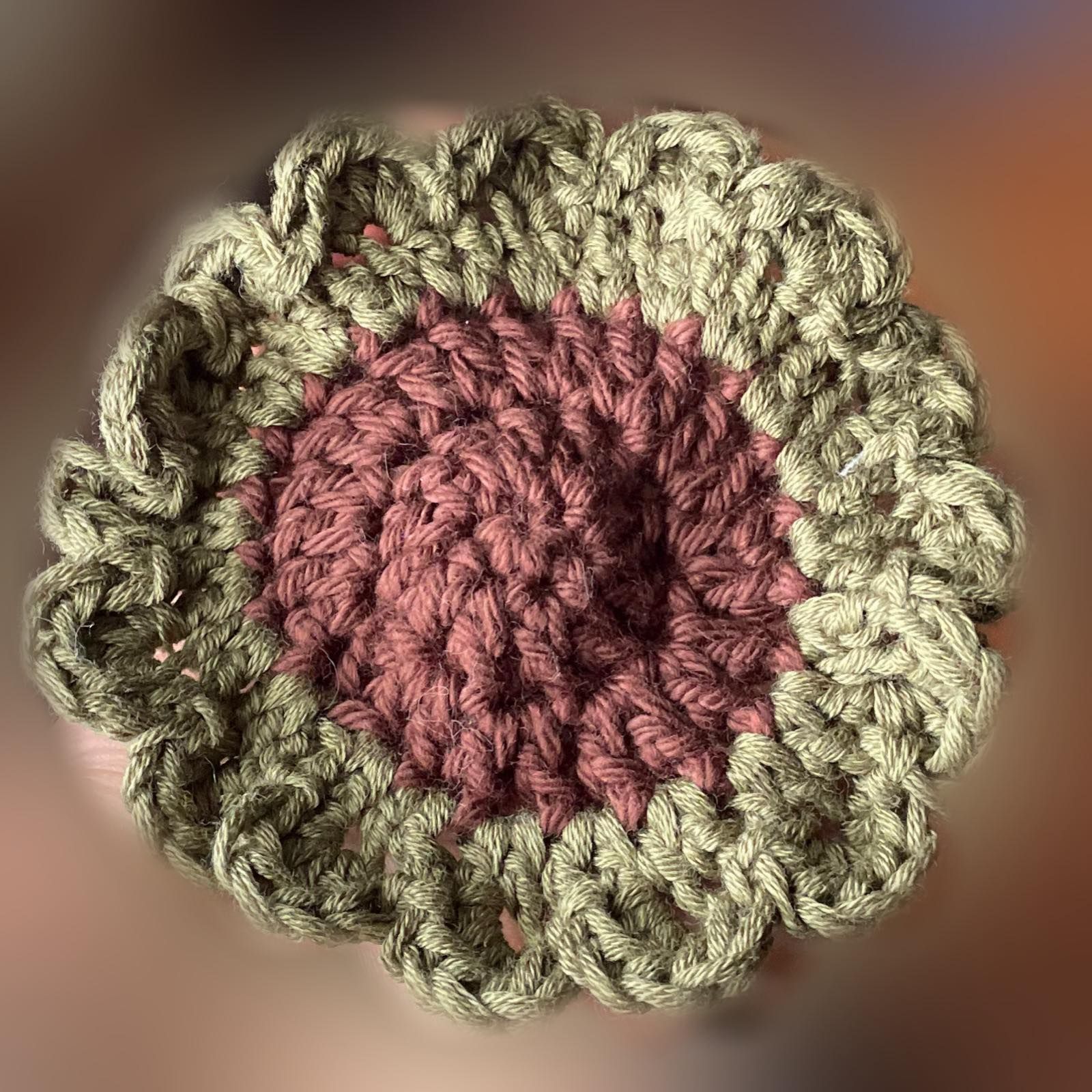 A close up of a crocheted flower on a blurry background.