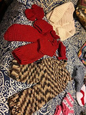 A bunch of hand  crocheted clothes are laying on a bed.