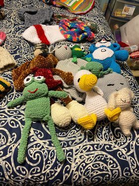 A bunch of hand  crocheted stuffed animals are sitting on top of a bed.