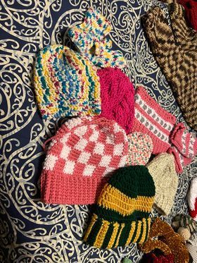 A bunch of  hand  crocheted hats are sitting on top of a bed.