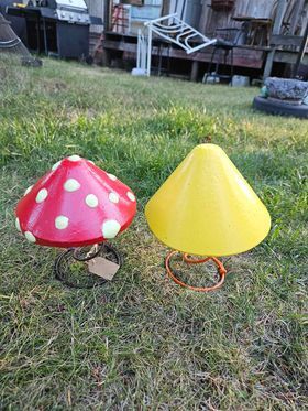 Two mushroom shaped concrete yard decorations are sitting on top of a lush green field.