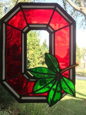 A stained glass letter o with a green leaf on it