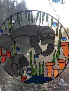 A stained glass window hanging with a manatee on it