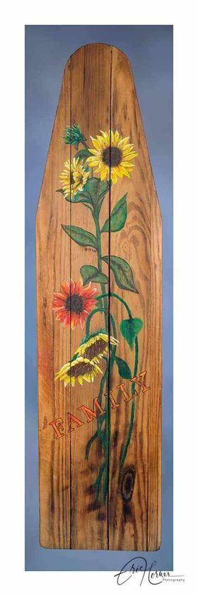 A wooden ironing board with sunflowers painted on it.