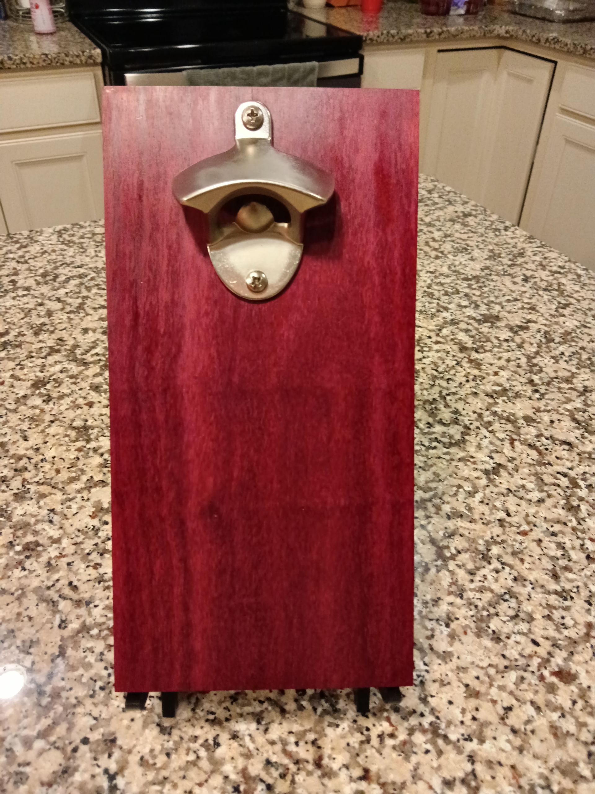 A wooden bottle opener is sitting on top of a granite counter.