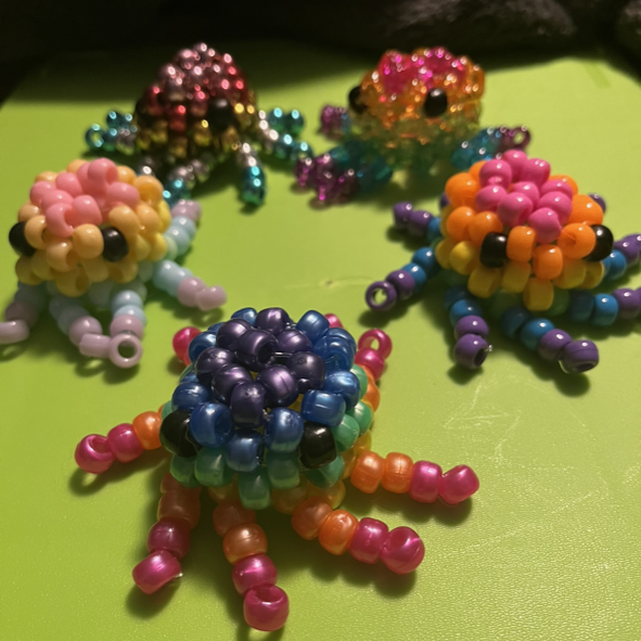 A group of beaded octopus are sitting on a green surface.