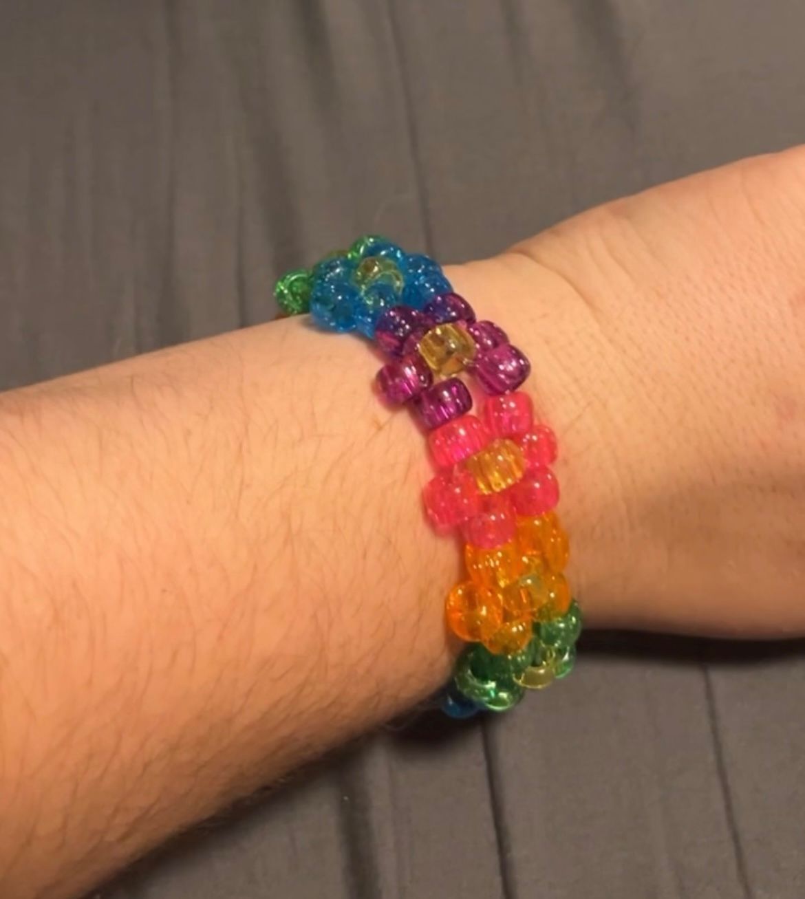 A person wearing a rainbow colored bracelet on their wrist