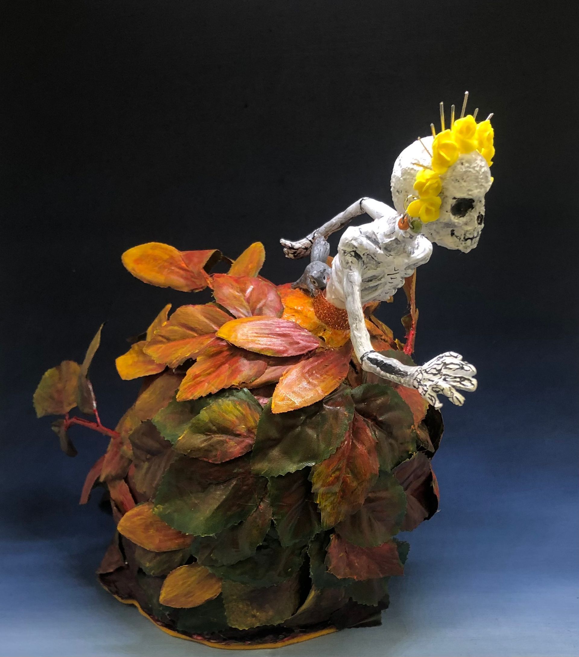 a skeleton is wearing a dress of autumn orange colored leaves