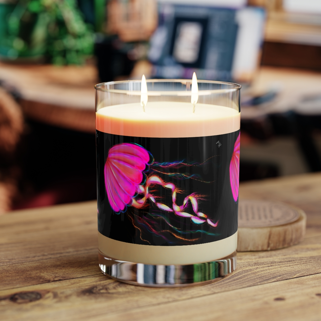 A candle with a jellyfish on it is sitting on a wooden table.