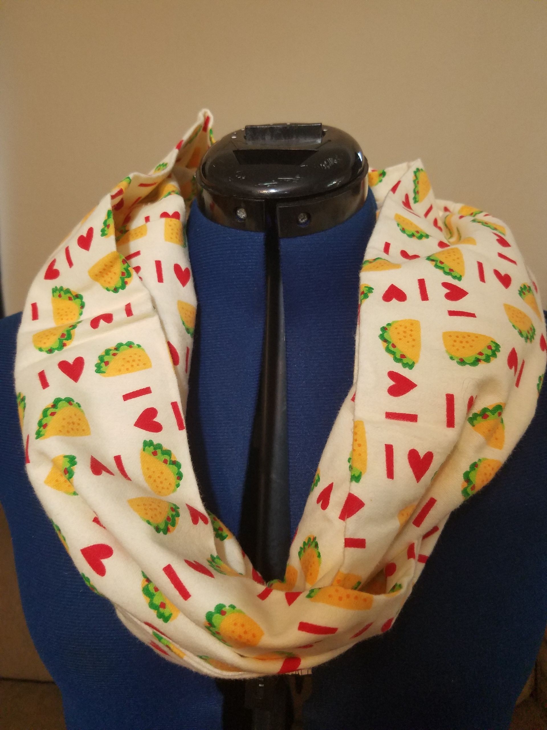 A scarf with tacos and hearts on it is on a mannequin
