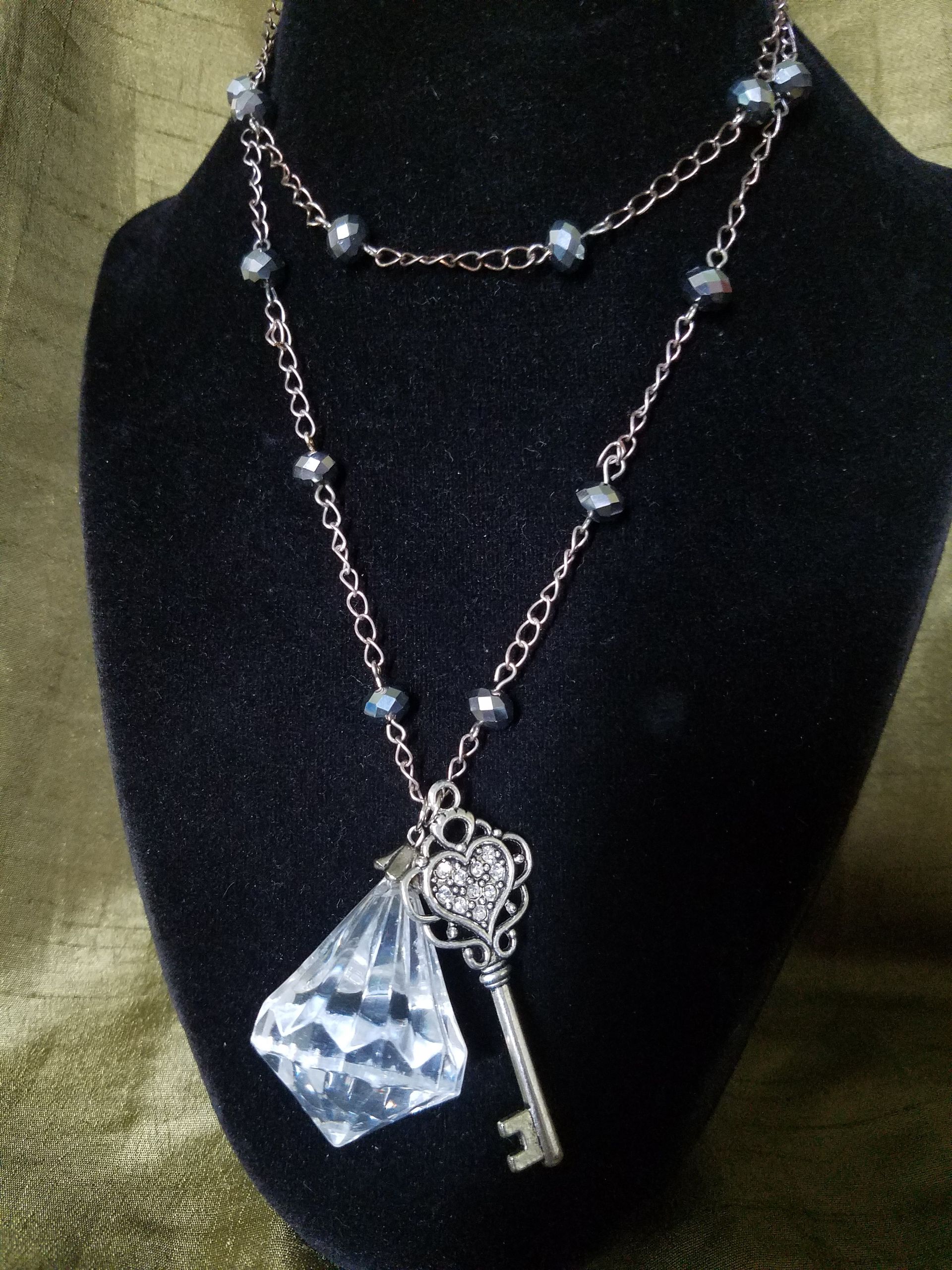 A mannequin is wearing a necklace with a key pendant