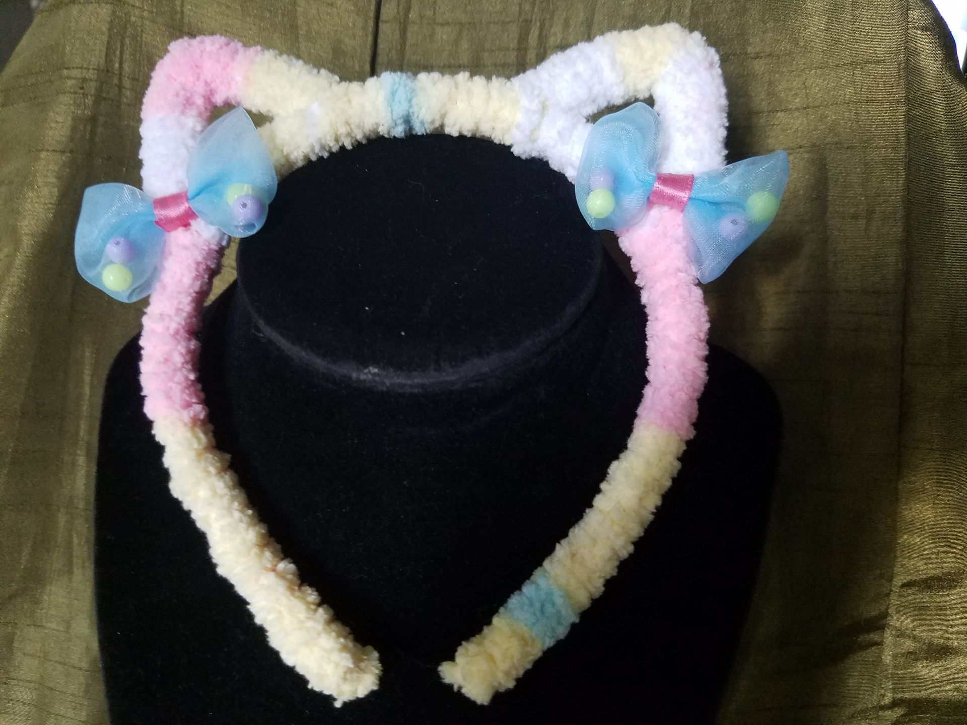 A pink white and blue headband with bows on it