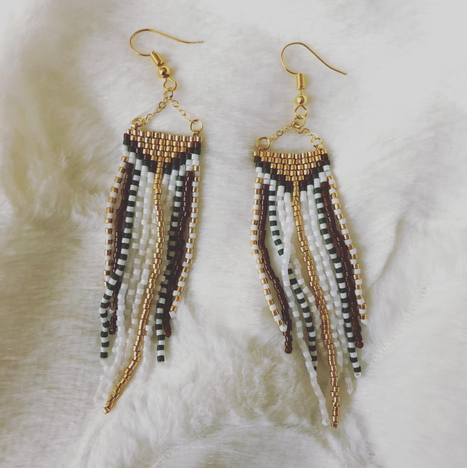 A pair of beaded earrings are sitting on a white cloth