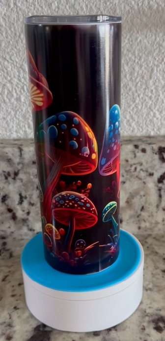 A stainless steel tumbler with mushrooms on it is sitting on a table.