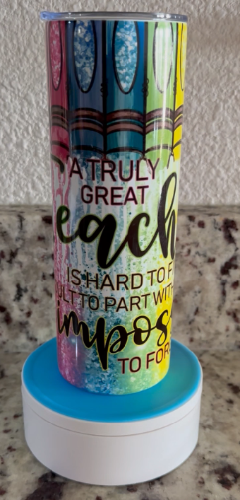 A stainless steel tumbler with crayons on it is sitting on a table.